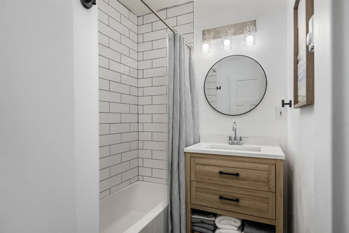 An inviting bathroom scene with a large mirror, softly lit vanity, sleek shower area, and warm lighting. The contemporary styling and serene mood reinforce the sense of a comfortable retreat within the home.